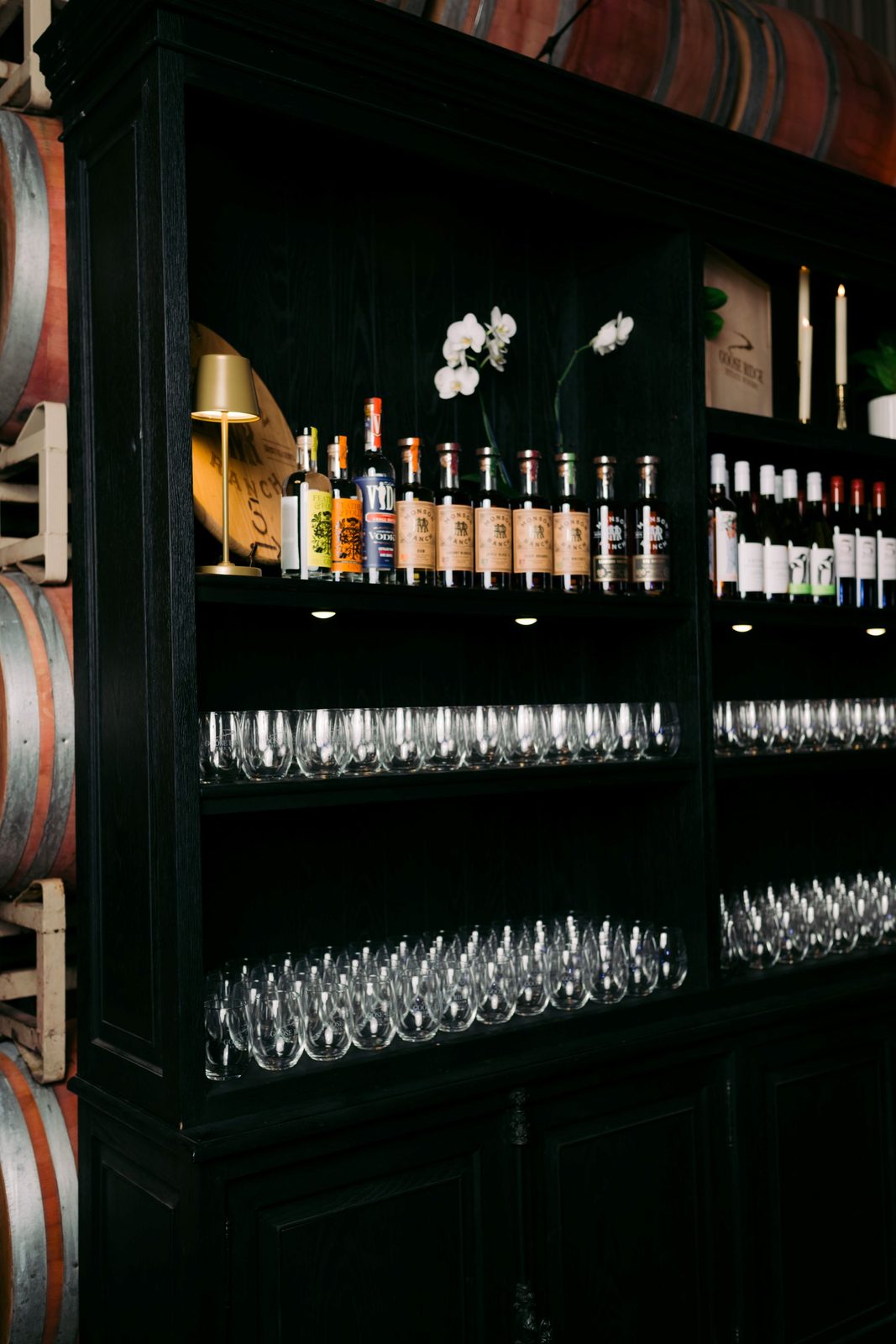 Bar stocked with Goose Ridge wines and stemless glassware in a black hutch among the barrels at The Barrel Hall