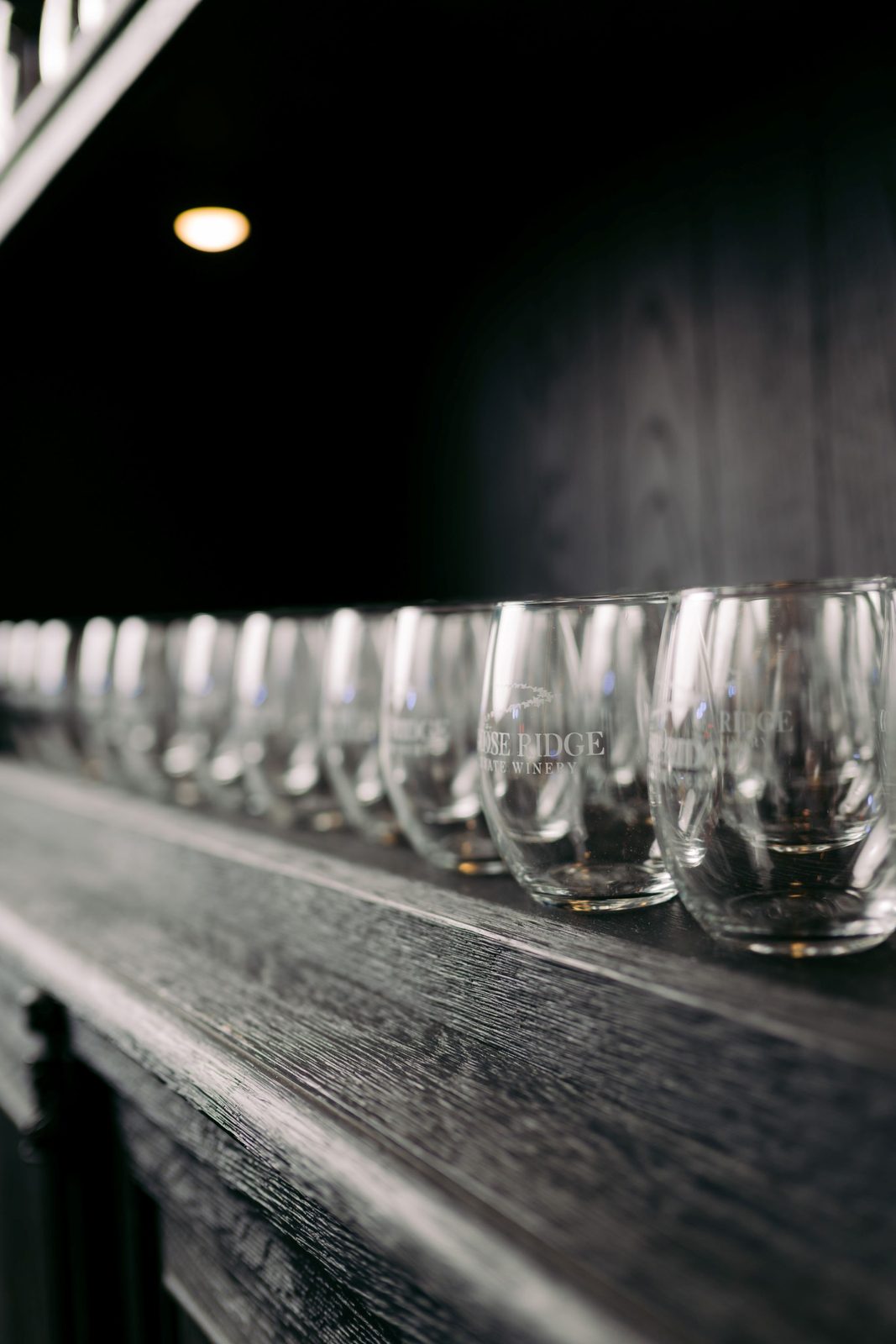 Rows of Goose Ridge Estate Winery glasses lined up along the bar at The Barrel Hall