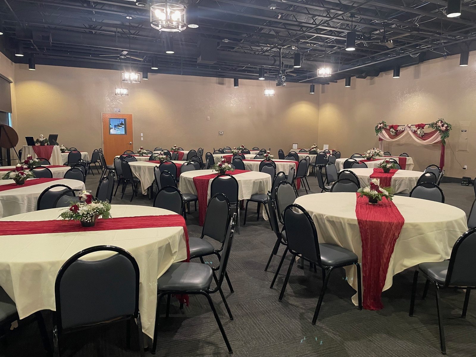 The CG Event Center dressed for a reception with red-and-white table settings and a decorated backdrop