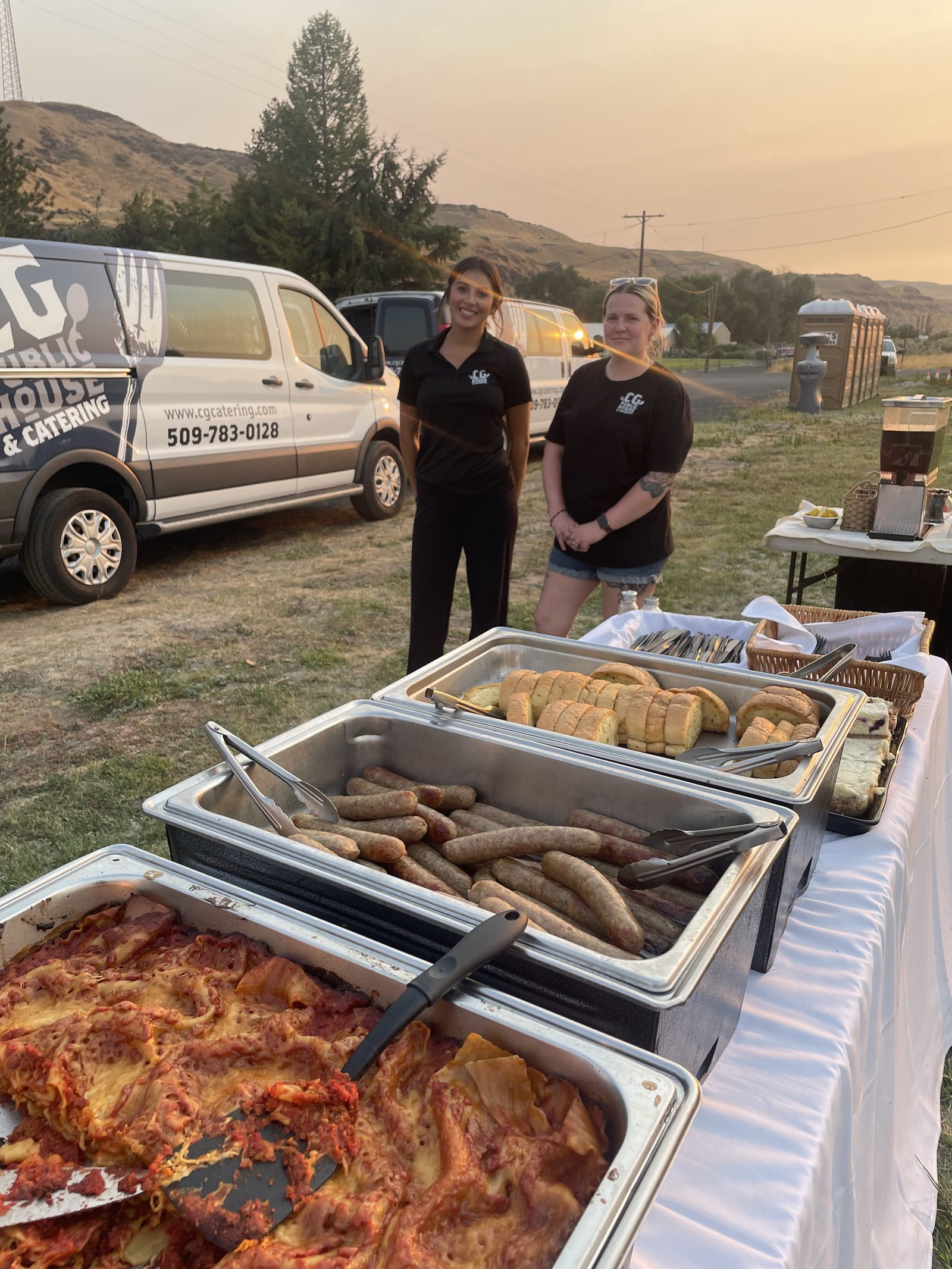 The CG Public House & Catering van and team serving a hot buffet of lasagna, sausage, and garlic bread to fire crews at the Lyons Ferry Fire base camp near Kahlotus, Washington, at sunset