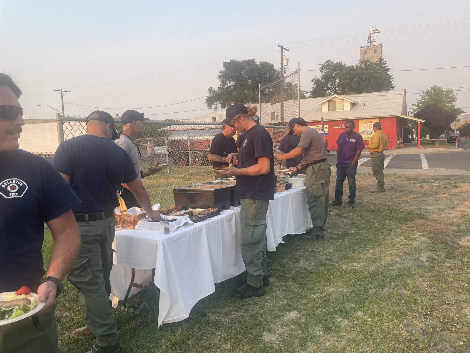 Wildfire crews going through a CG Public House & Catering hot buffet line at the Lyons Ferry Fire base camp near Kahlotus, Washington, under a smoke-filled sky