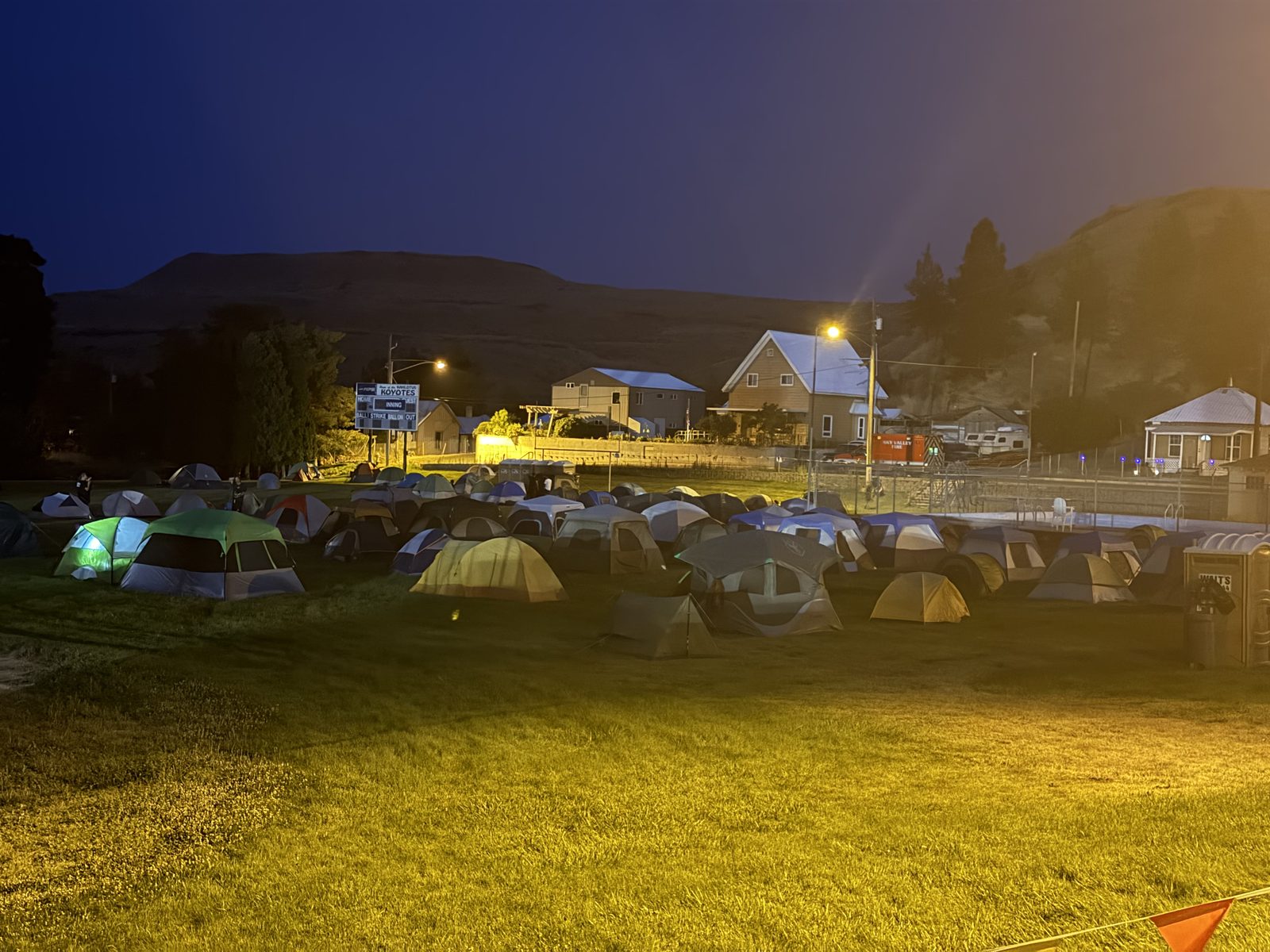 The Lyons Ferry Fire base camp at night near Kahlotus, Washington, rows of crew tents lit by light towers where fire personnel rest between shifts