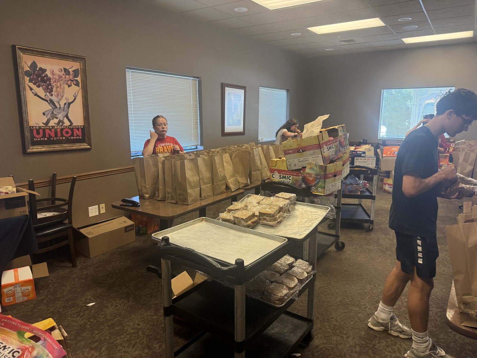 The CG Public House & Catering team assembling sack lunches, with rows of brown-bag lunches and trays of fresh sandwiches, to send out to the crews on the fire line