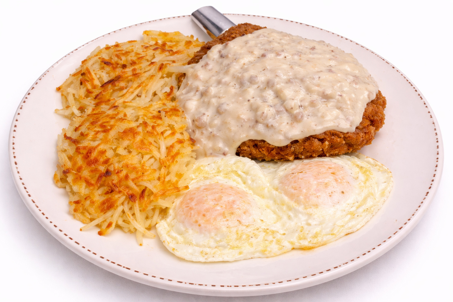 Chicken fried steak smothered in country gravy with hash browns and two fried eggs