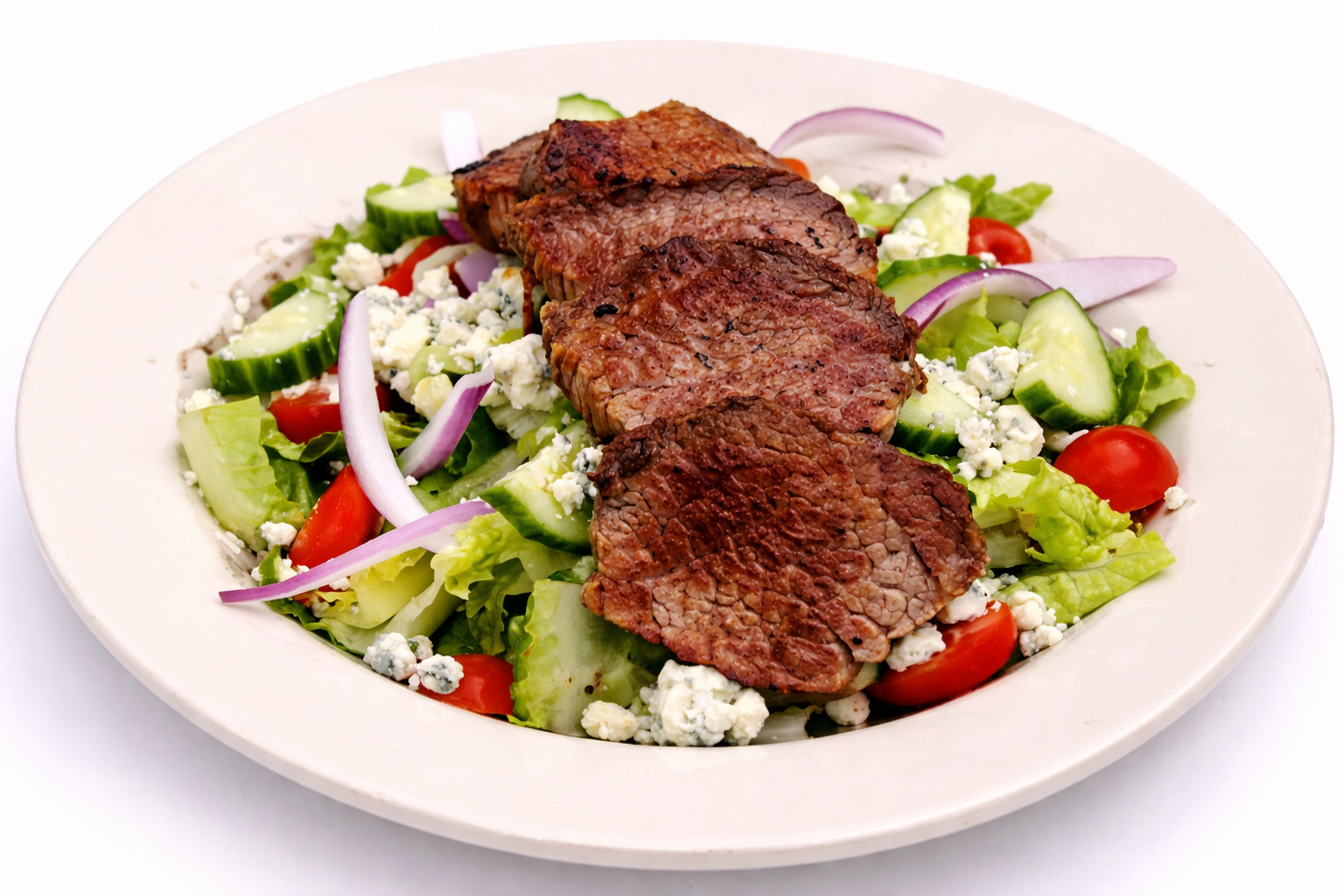 Sliced London broil over a salad with blue cheese crumbles, cherry tomatoes, cucumber and red onion