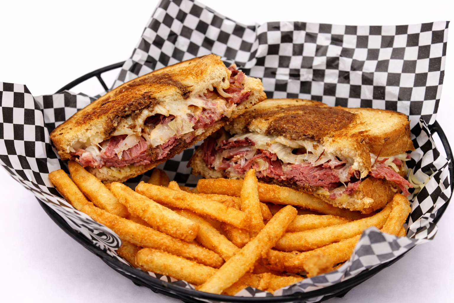 Grilled Reuben sandwich on marbled rye stacked with corned beef and sauerkraut, served with fries